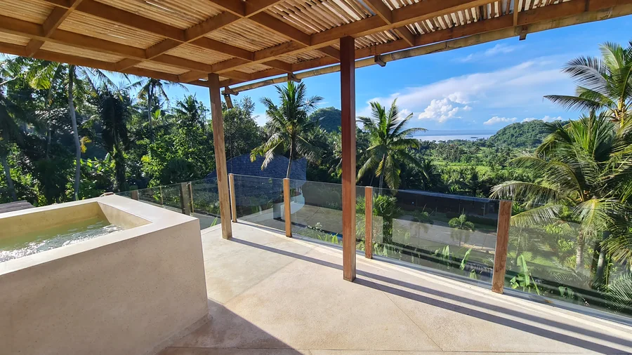 A covered hotel terrace looking over palms towards the sea