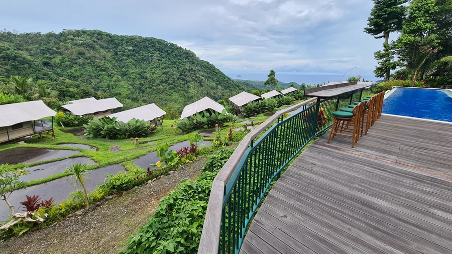 A hotel with a pool, green hills and sea views in East Bali