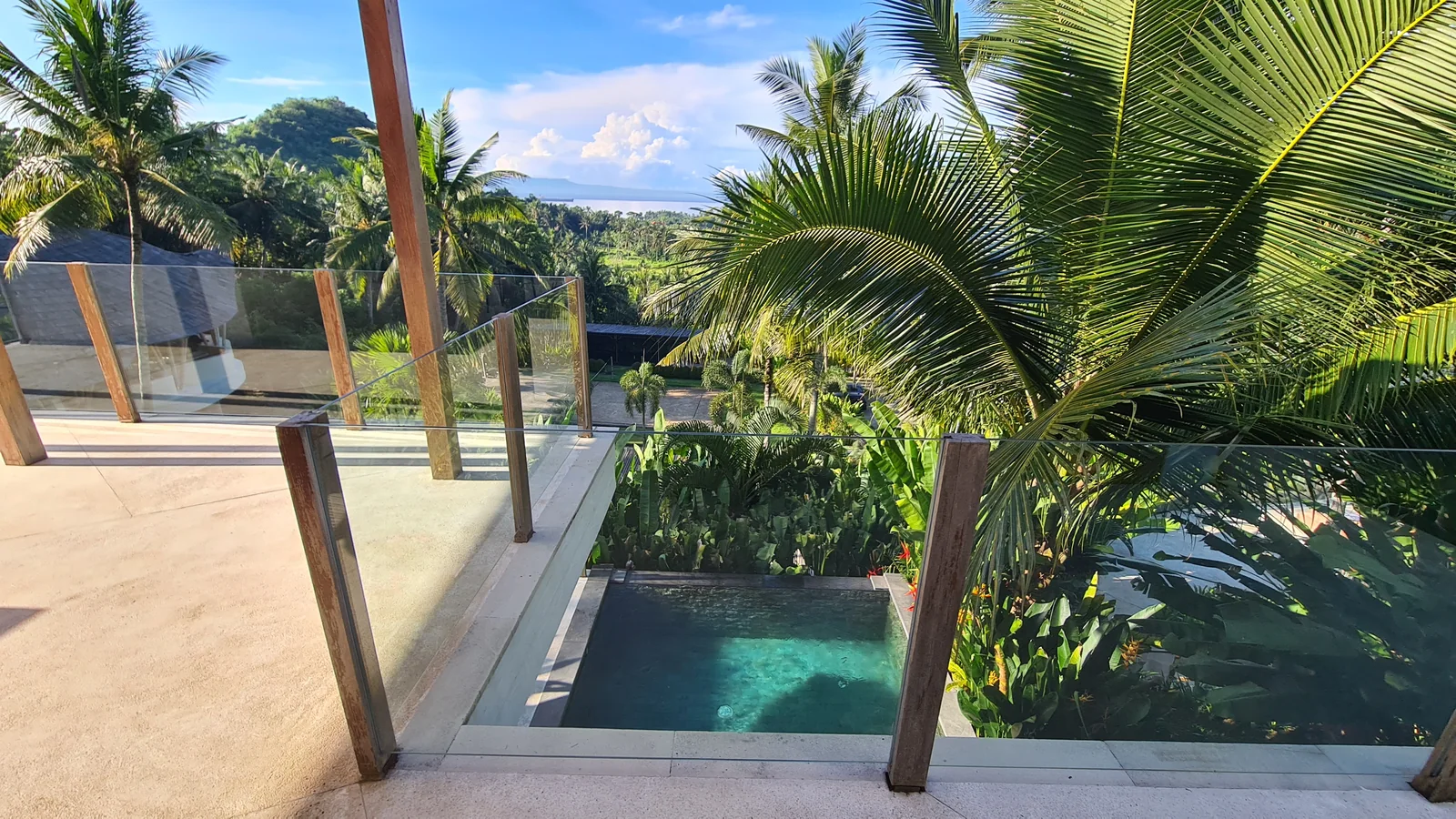 A private hotel pool with palms, a terrace and sea views in East Bali